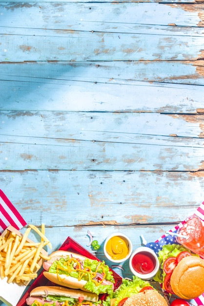Foto picknickfeest met watermeloen, hamburgers, hotdogs, drankjes, blauwe houten buitentafelachtergrond