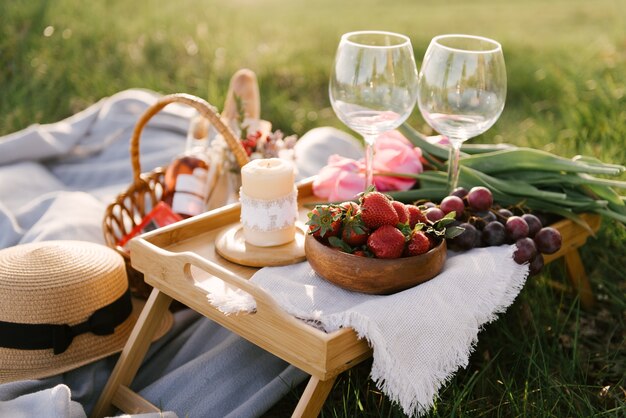 Picknickmand met aardbeien, druiven en broodjes op het groene gras in de tuin