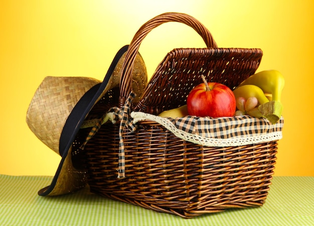 Picknickmand met fruit op doek op gele achtergrond