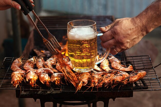 Picknickmensen koken langoustines op vuur met koud bier