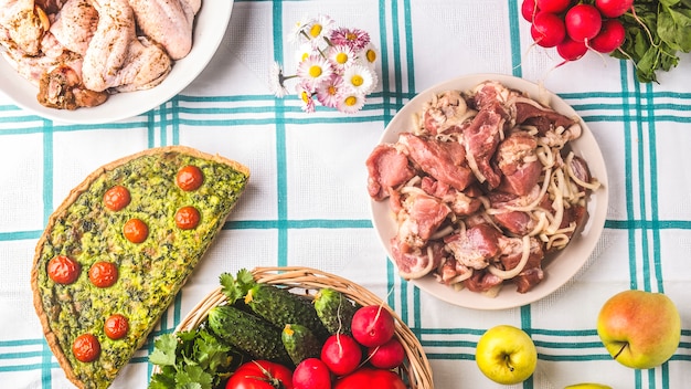 Picknicktafel met rauw gemarineerd vlees, groenten en cake. Zomertijd.