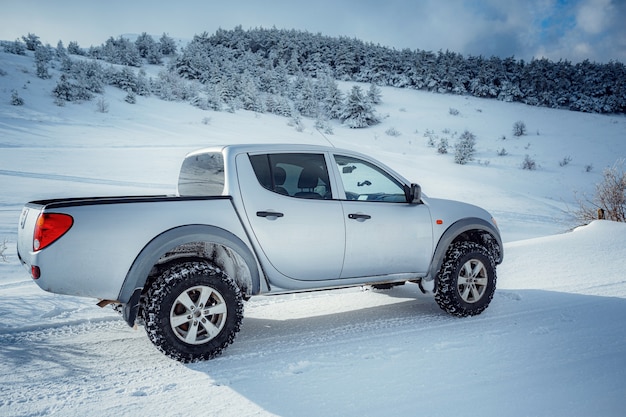 Pickup truck on road, Beautiful winter road under snow mountains. Shiny silver truck measuring the depth of the snow. idea and concept of freedom of movement in any weather