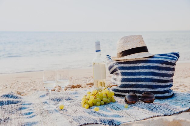 Picnic background with bag grape and white wine on the beach by blue sea