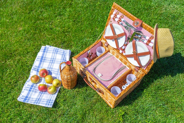Корзина для пикника на зеленой солнечной лужайке в парке