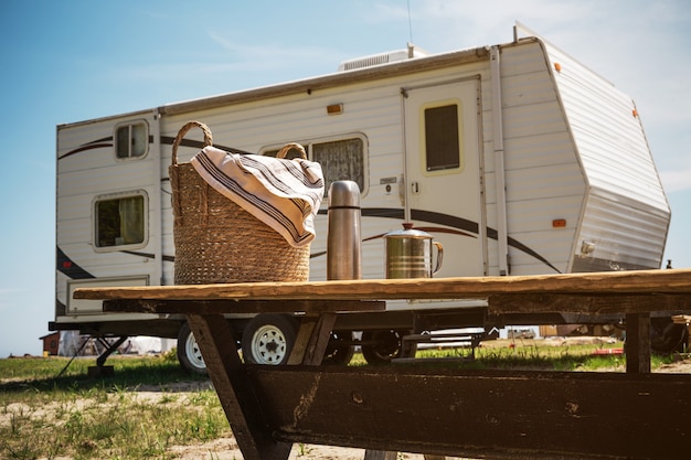 Picnic basket stands on a wooden table against the background of a travel trailer