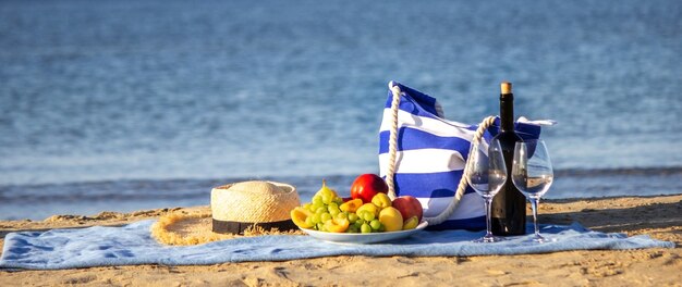 ピクニック毛布、ワイン、フルーツ、美しい海のビーチ自然選択的な焦点