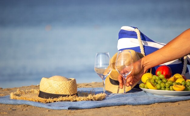 Picnic blanket, wine, fruit, beautiful sea beach. Selective focus