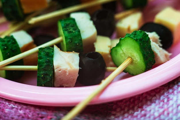 Foto picnic canapes groene komkommer zwarte olijven kaas op houten stokken appetizer voorgerechten op een bord macro