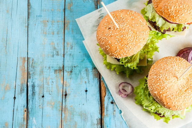 Picnic Fast food Unhealthy food Delicious Fresh Tasty Burgers with Beef Cutlet fresh Vegetables and Cheese on old rustic blue wooden table with sweet soda water  