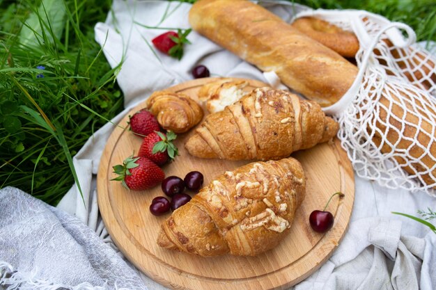 Picnic in the field with berries juice cheese sausage and sweet croissants