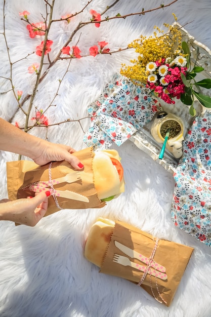 Picnic lunch in the park. Sandwiches, apples and flowers.