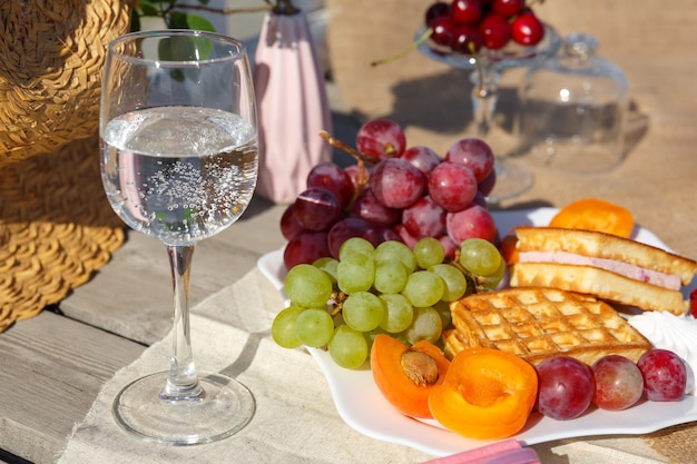 Пикник на природе. Тарелка с фруктами и вафлями и стакан воды стоит на мешковине