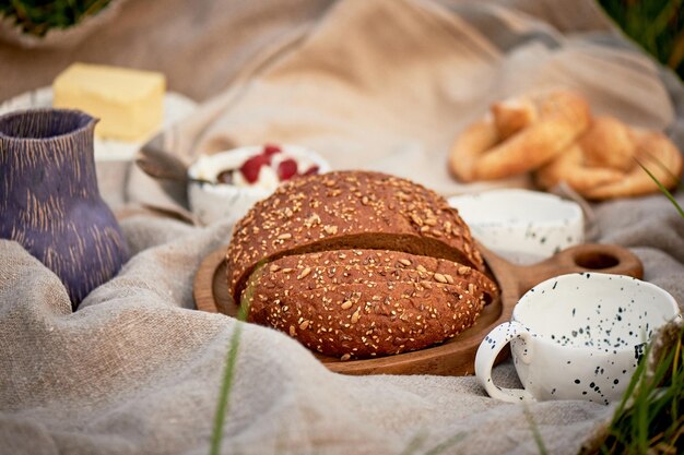 Пикник на природеСвежий хлеб с крупами на деревянной доске льняная скатерть керамика Экостиль
