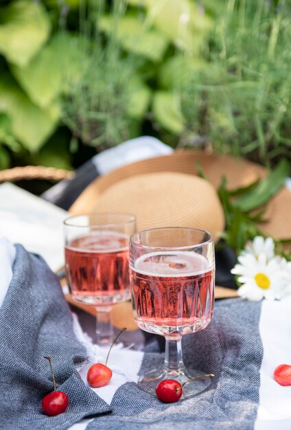 Picnic outdoors in lavender fields.  Rose wine in a glass, cherries and straw hat on blanket