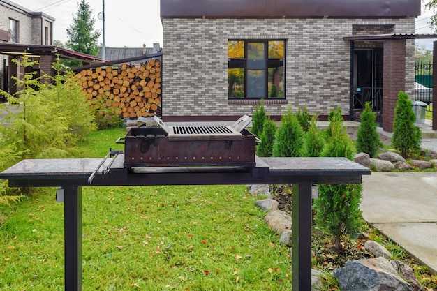 Posto per picnic con barbecue sullo sfondo di una casa di campagna.