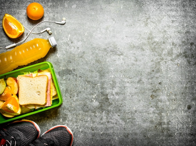 Il set da picnic panini, succo d'arancia e frutta sul tavolo di pietra