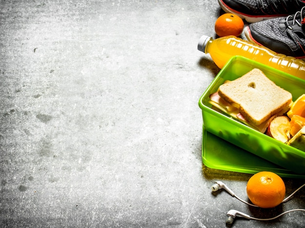 The picnic set. Sandwiches, orange juice and fruit. On the stone table