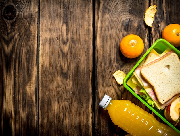 The picnic set. Sandwiches with cheese and bacon, fruit and orange juice.