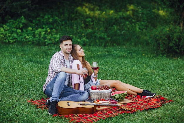 Picnic time. Man and woman in park with red wine