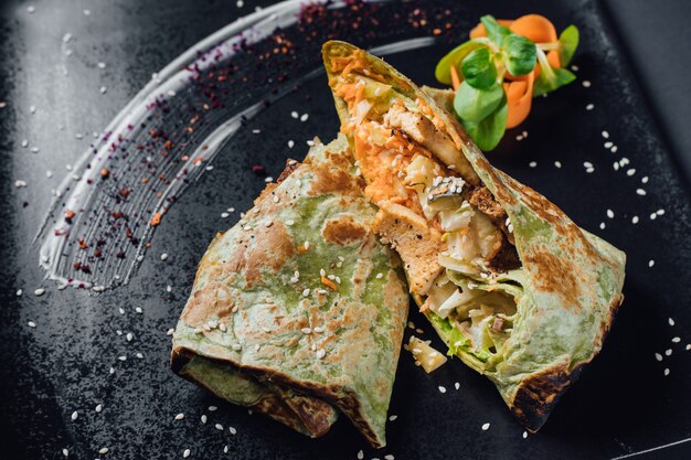 Picnic. vegetarian Wrap iceberg, pickled cucumbers, celery, carrot, tofu. on plate, isolated on black background, close up, top view