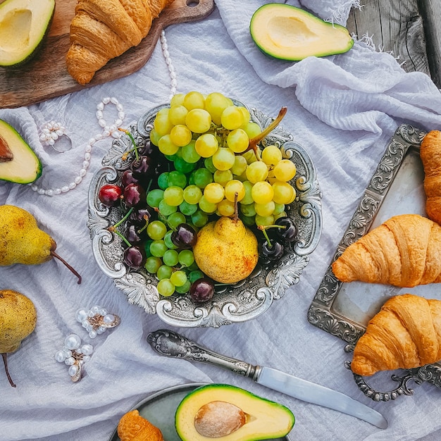 Picnic in vintage style, Fruits and bread with vintage dishes, decorations on a wooden background near the water, Top view