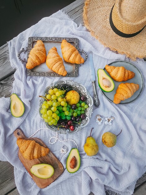 Picnic in vintage style, Fruits and bread with vintage dishes, decorations on a wooden background near the water, Top view