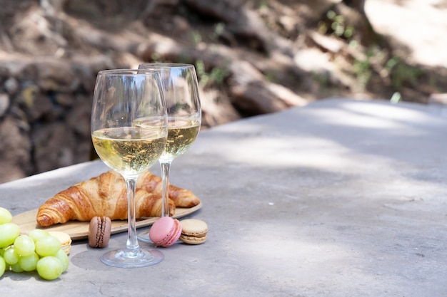 Picnic with white wine and croissants in the forest