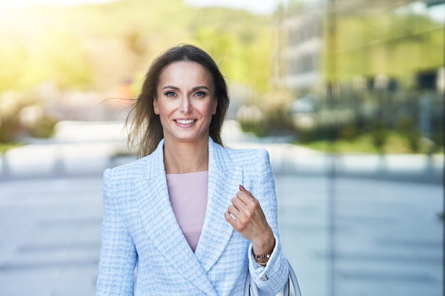 Picture of adult attractive woman with smartphone walking in the city