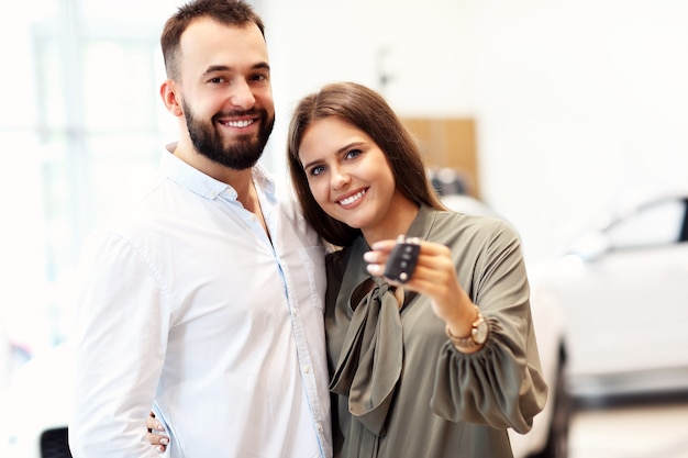 Picture of adult couple choosing new car in showroom