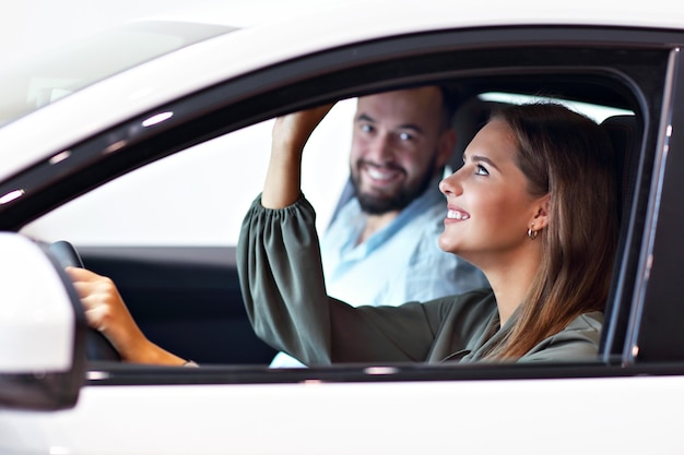 Picture of adult couple choosing new car in showroom