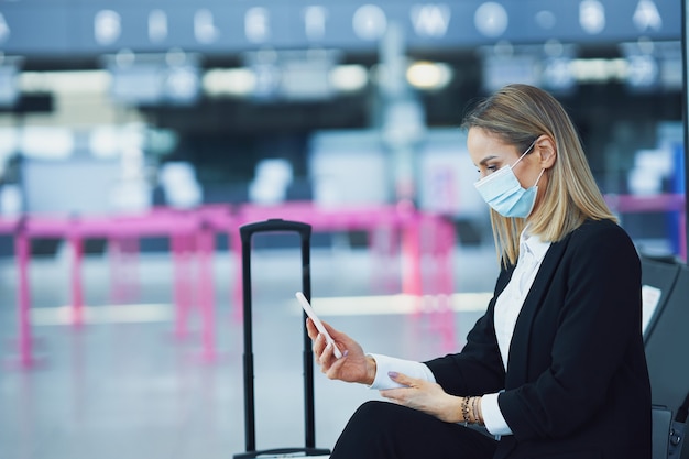 Foto immagine di una passeggera adulta che utilizza lo smartphone in aeroporto