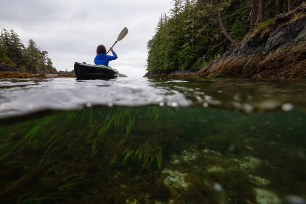 Over and Under picture of an Adventurous woman kayaking in the Pacific Ocean