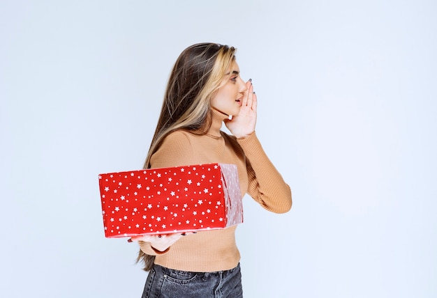 Picture of an attractive woman model holding a red present.