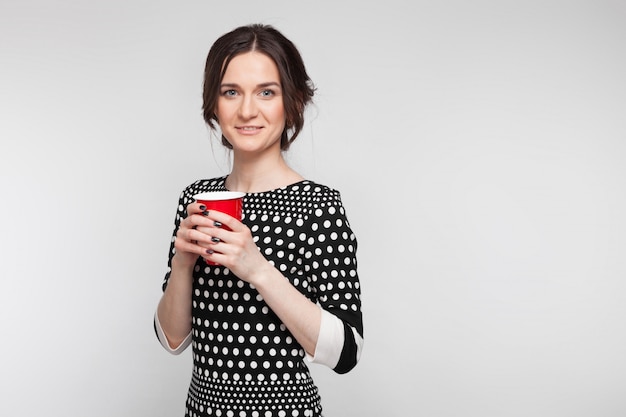 Картина привлекательная женщина в крапчатой одежде, стоя с чашкой в руках