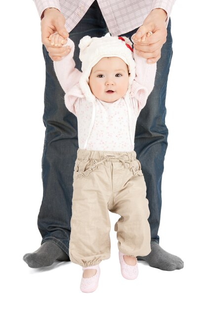 父親の助けを借りて最初の一歩を踏み出す赤ちゃんの写真