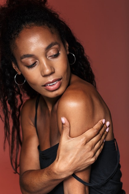 Picture of a beautiful african young woman isolated over red wall.