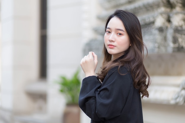 Una foto di una bellissima donna asiatica dai capelli lunghi in una veste nera che cammina e guarda fuori