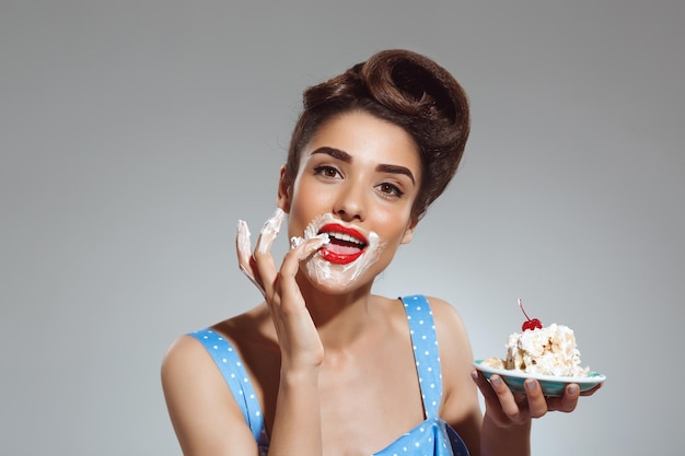 Picture of beautiful pinup girl eating cake at studio