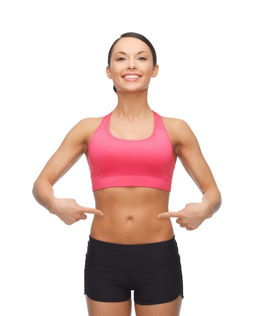 picture of beautiful sporty woman pointing at her six pack