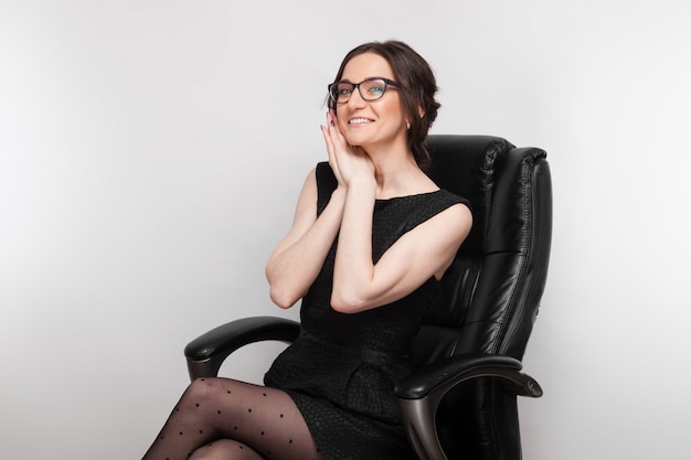 Picture of beautiful woman in black dress sitting in the armchair