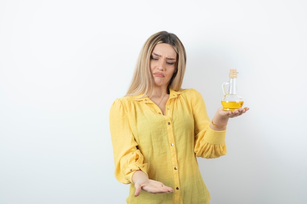 Picture of a beautiful woman model in yellow shirt holding a glass bottle of oil