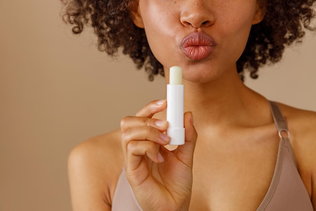 Picture of beautiful woman with lip balm indoors