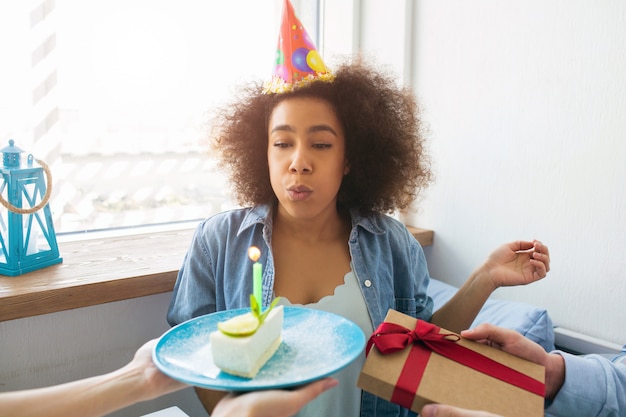 A picture of birthday girl blowing up the candle and getting a present from her friends.