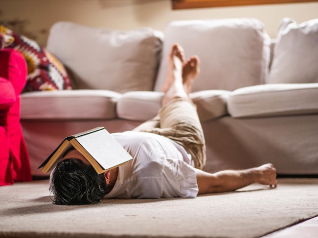 Picture of a brunette male laying on the ground with a book on his face