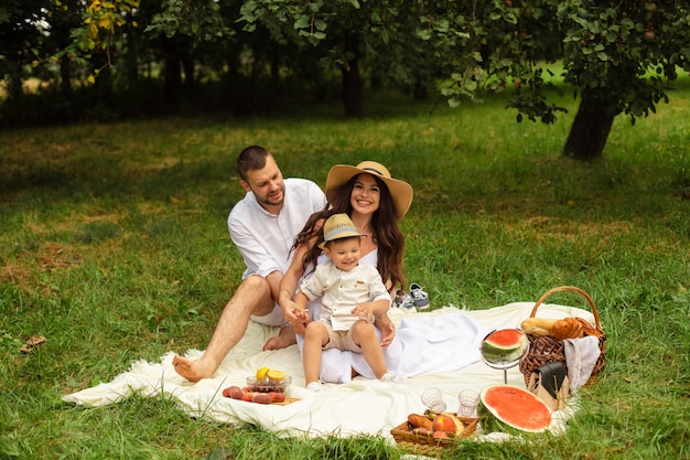 Foto di allegra mamma caucasica, papà e il loro bambino si divertono insieme e sorridono in giardino