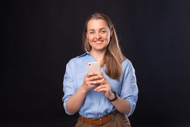 A picture of a cheerful woman smiling at the camera and chatting on her phone with someone