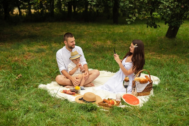 L'immagine della giovane femmina e del maschio caucasico allegri tiene il loro bambino sulle mani, sorride e si rallegra