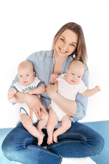 Picture of cheerful young caucasian female sits with her children smiles and hugs them