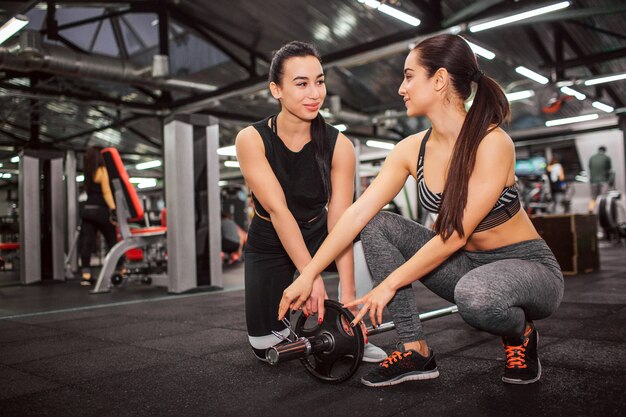 Picture of cheerful young women stand on knees together and smile.