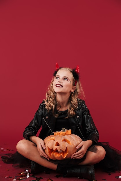 Изображение веселой маленькой девочки-дьявола в карнавальном костюме на хэллоуин